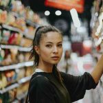 ragazza prende un prodotto dallo scaffale del supermercato