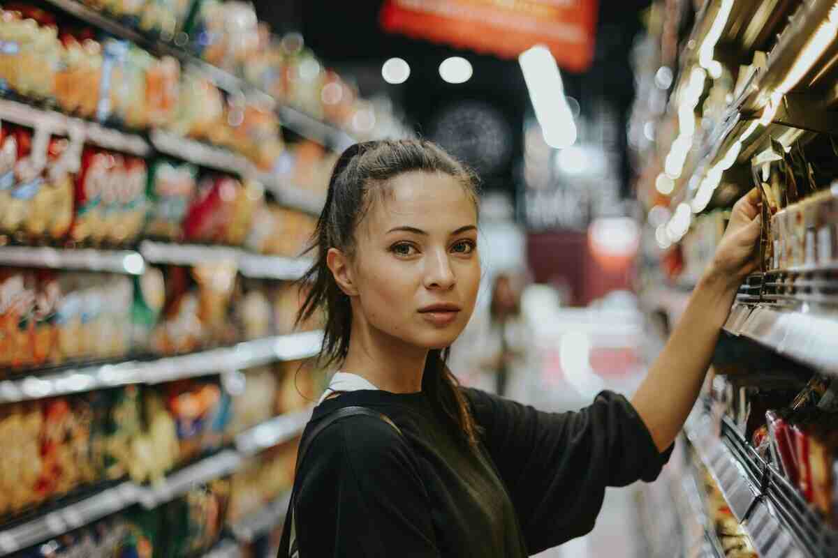 ragazza prende un prodotto dallo scaffale del supermercato